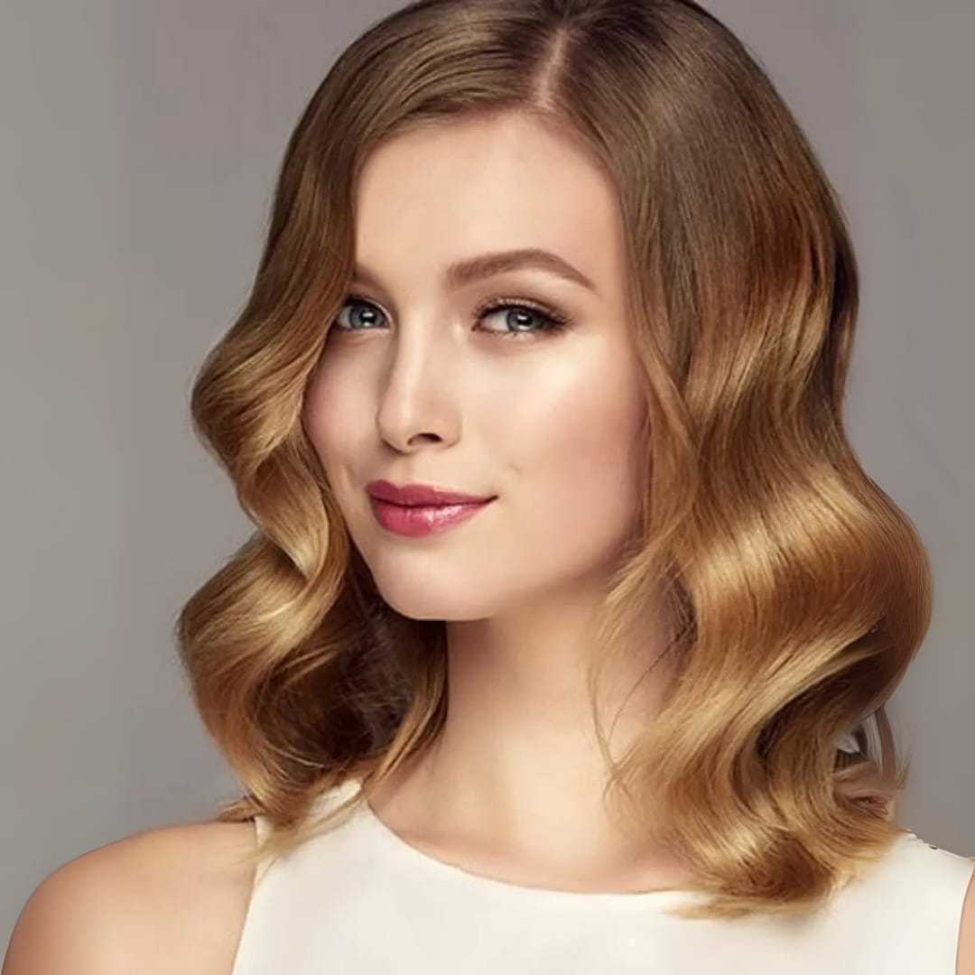 Woman with wavy blonde hair and a confident smile, wearing a white top.