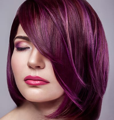 Portrait of beautiful fashion model woman with short purple colored hairstyle and makeup with calm closed eyes. indoor studio shot, isolated on gray background.